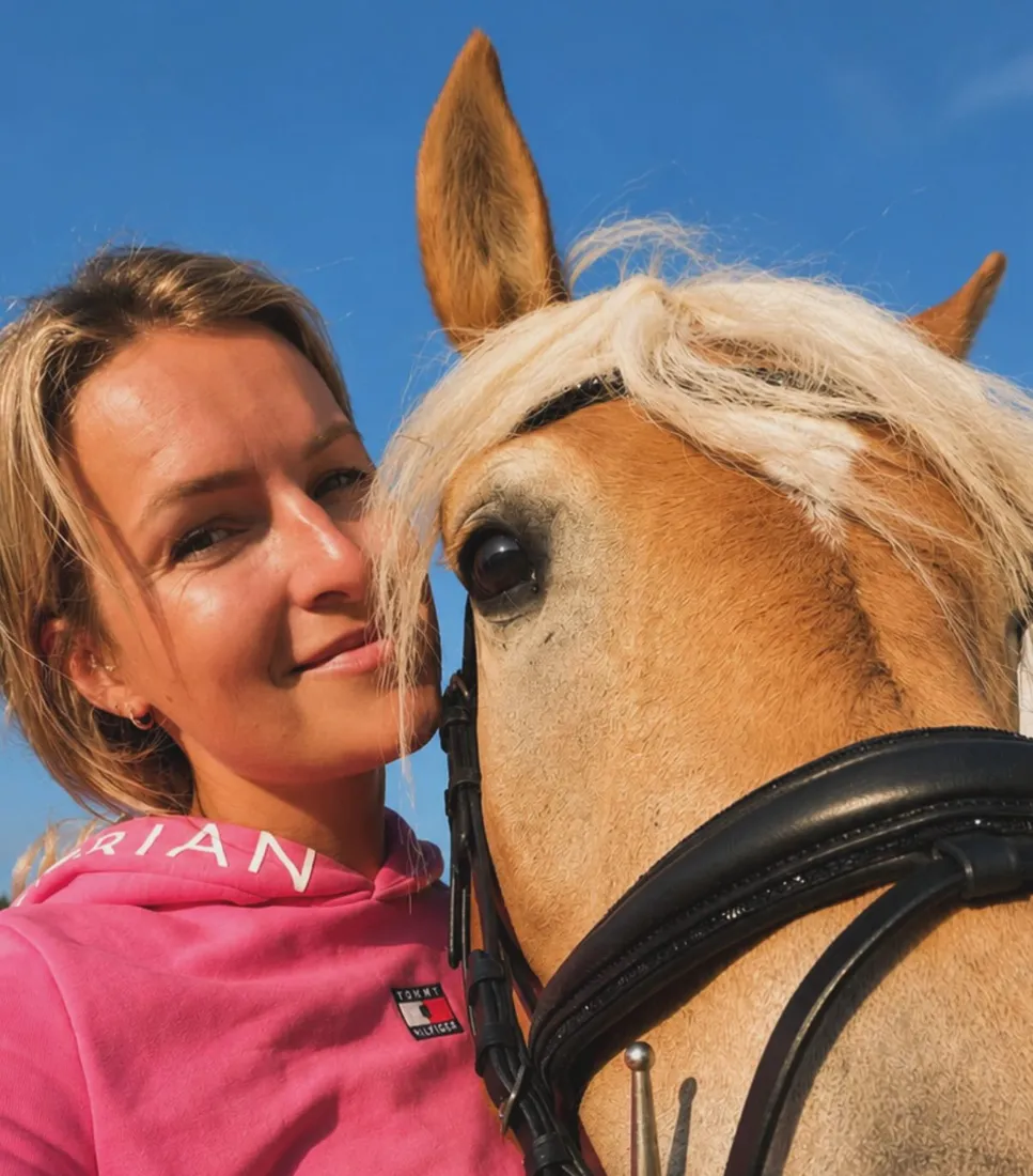 Isa lächelnd neben einem Haflinger